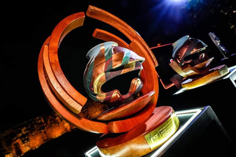 Trofeos en forma de cascos de piloto, destacando placas con '1ST PLACE' en un ambiente formal y elegante.
