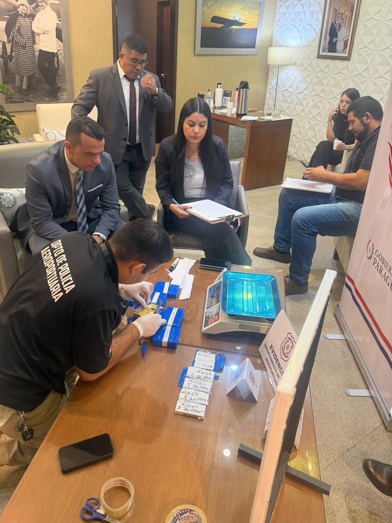 El fiscal de Crimen Organizado, Carlos Alejandro Cardozo Pereira, observa sentado la incautación del oro en el aeropuerto de Luque.