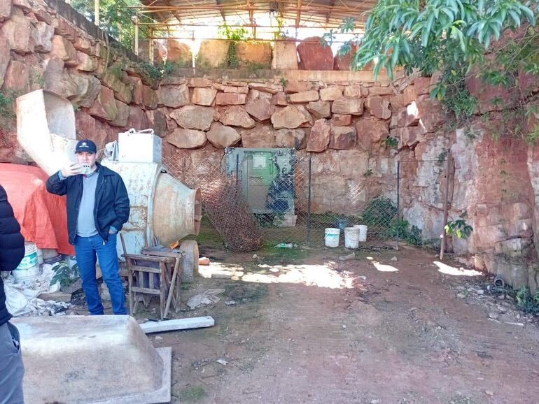 Dos personas en la cantera Ita Bella; una toma fotos con un dispositivo, la otra observa. Fondo de piedras y vegetación.