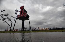 Letrero grande que dice 'TE AMO Yo Encarnación' en un parque desolado con cielo nublado y vegetación escasa.