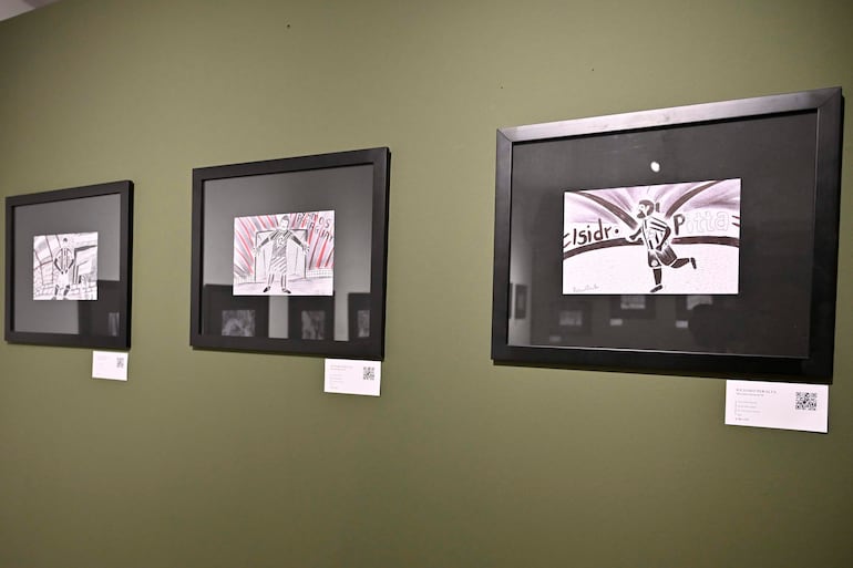 Tres dibujos enmarcados que representan a jugadores en acción, expuestos en pared verde.