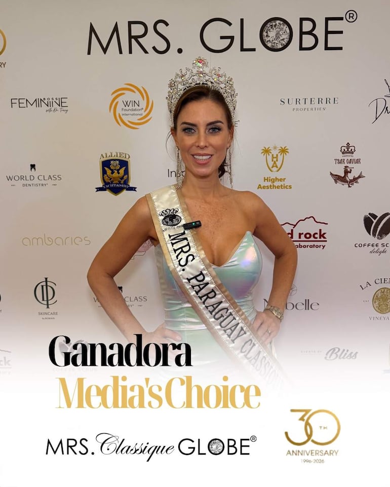 Mujer con corona y banda de Mrs. Paraguay Classique sonríe frente a un fondo de logotipos de patrocinadores.