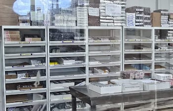 Estante de farmacia con envases de medicamentos organizados y etiquetas visibles en un ambiente limpio y bien iluminado.