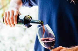 Un hombre sirve una copa de vino en una copa.