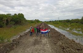 Voluntarios de la zona de Fuerte Olimpo, muestran la tricolor luego de completar la tarea de desagote del camino y permitir la rehabilitacion