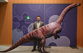 Franco Claretti, director del área de Lombardía del Parque Nacional del Stelvio, posa para una fotografía con un dinosaurio de cartón durante una conferencia de prensa para presentar el descubrimiento de miles de huellas de dinosaurios halladas en el Parque Nacional del Stelvio, en Italia, cerca de las zonas que albergarán los Juegos Olímpicos de Milán-Cortina 2026, en Milán, el 16 de diciembre de 2025.