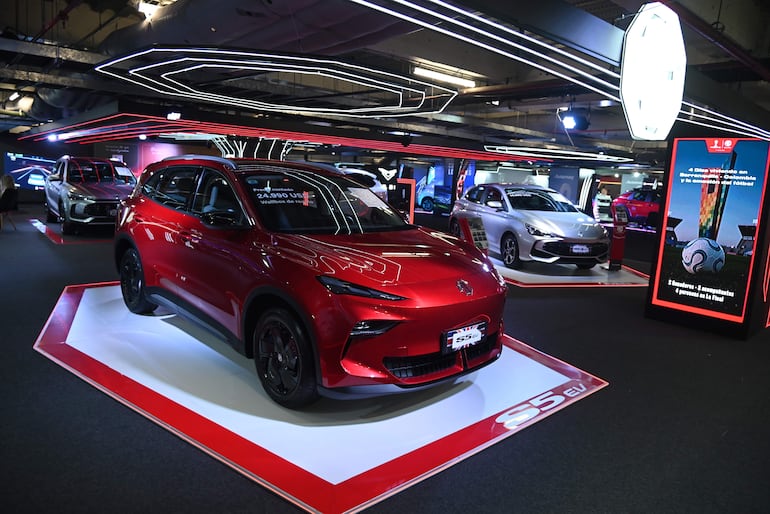 Exhibición de SUV roja con precio visible y otros autos, sin personas presentes, en un ambiente moderno y iluminado.