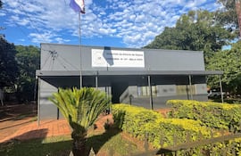 Fachada de la Comisaría 14 en Bella Vista, con escudo policial y banderas, rodeada de vegetación.