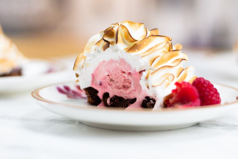 Bomba de helado flambeado con base de turrón y nueces y helado de frambuesa, un postre impactante.