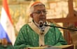 Adalberto Martínez, de cabello blanco y gafas, habla en vestimenta religiosa verde, junto a figuras similares, con banderas al fondo.
