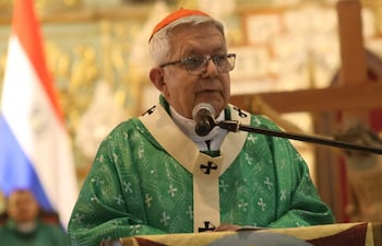 Adalberto Martínez, de cabello blanco y gafas, habla en vestimenta religiosa verde, junto a figuras similares, con banderas al fondo.