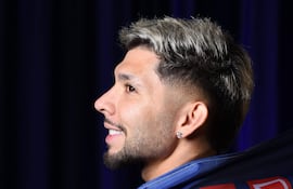 Ramón Sosa sonriente, con camiseta azul y detalles en rojo y blanco del Ipswich Town, en un fondo oscuro.