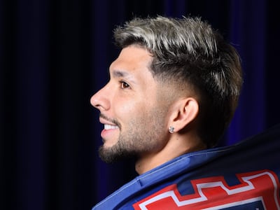 Ramón Sosa sonriente, con camiseta azul y detalles en rojo y blanco del Ipswich Town, en un fondo oscuro.