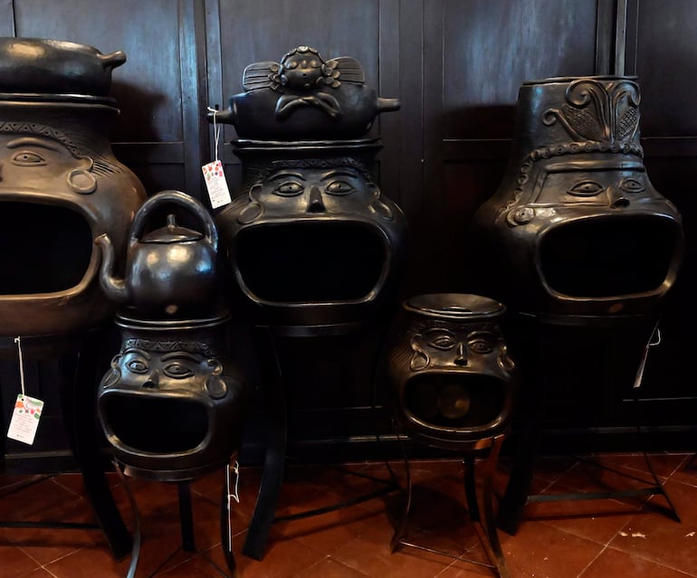 Cerámicas negras con formas antropomórficas sobre fondo oscuro, iluminadas para resaltar detalles expresivos.