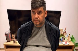 Hombre sentado con barba y camiseta gris, serio y en un entorno hogareño, durante su detención en Encarnación.
