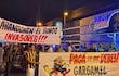 Grupo de hinchas con camisetas amarillas y negras sosteniendo pancartas contra el bingo, en un ambiente nocturno.