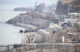 Un grupo de migrantes camina por la orilla, cerca de la valla fronteriza que separa Marruecos del enclave español de Ceuta, en el norte de África, mientras regresan a territorio marroquí; imagen captada desde Ceuta el 1 de agosto de 2026.