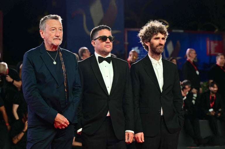 Steven Knight, Dylan Southern y Will Lovelace, el creador y los directores del documental "Oasis: Don't Look Back in Anger" en la alfombra roja de Venecia. (Photo by Stefano RELLANDINI / AFP)