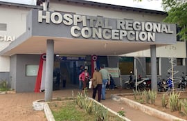 Mujer con mochila rosada y hombre de espaldas en la entrada del Hospital Regional, donde se realiza vacunación Covid-19.