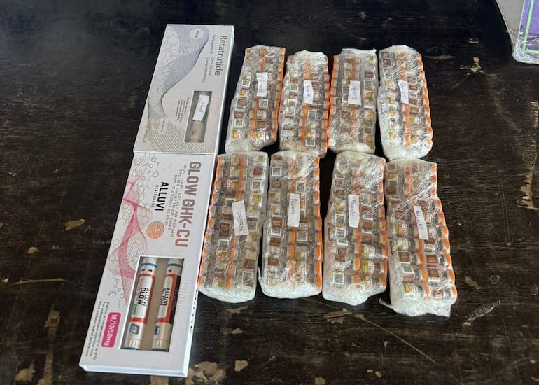 Frascos y cajas de medicamentos sobre una superficie oscura en un ambiente de consultorio.