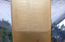 Escena de inundación en Carapeguá, con edificio azul afectado y objetos como sillas y un balde anegados.