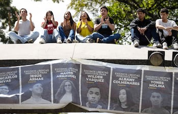Estudiantes sostienen una pancarta con imágenes de presos políticos, en Venezuela.