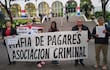 Grupo de manifestantes, incluyendo una mujer con pancarta grande sobre mafia de pagarés, frente al Palacio de Justicia.