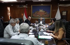Isaías Ricardo Fretes gesticulando mientras habla, sentado junto a José Jara Rojas, en ambiente de reunión formal con decoraciones paraguayas.