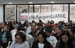 Gran reunión en salón con personas vestidas casualmente, atentos y algunos mirando sus teléfonos, pancarta destacada sobre ANDE.