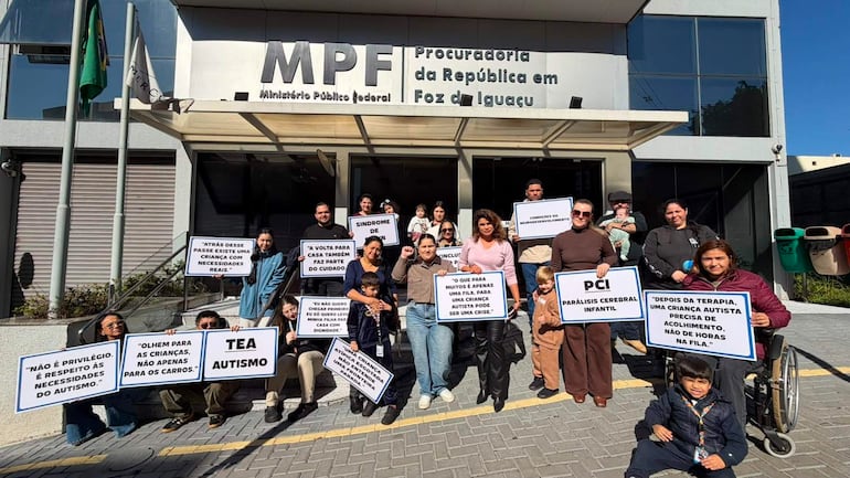 Grupo de personas con carteles abogando por derechos de niños con TEA, destacando una mujer en silla de ruedas en primer plano.