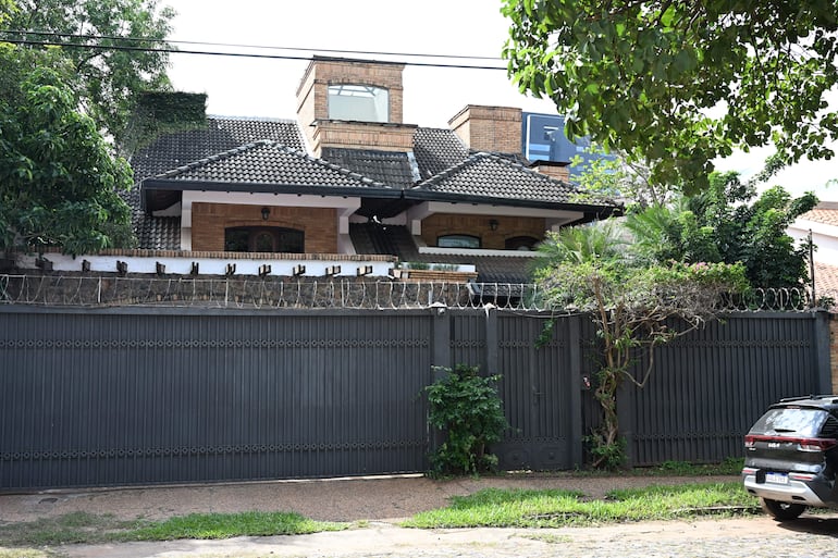 Casa contemporánea de Dalia López, rodeada de vegetación y con cerca de hierro negra.
