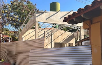 Ambiente de construcción con estructura de hormigón y tanque de agua en fondo, sin personas visibles.