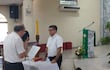 Ernesto Almada habla sosteniendo un micrófono mientras monseñor Osmar López lo escucha, en una iglesia con altar decorado.