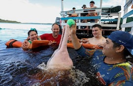El fisioterapeuta Igor Simoes Andrade y jóvenes con discapacidades nadan con delfines rosados (Inia geoffrensis) en el río Negro, en Iranduba, estado de Amazonas, Brasil.