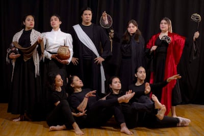 Grupo de ocho artistas en trajes dramáticos negros y acentos rojos, en dinámicas posturas de danza sobre un telón negro.