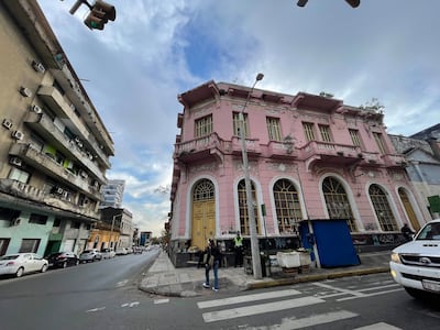 Calle desierta en Asunción, con un edificio rosa histórico a la derecha y modernos edificios a la izquierda.