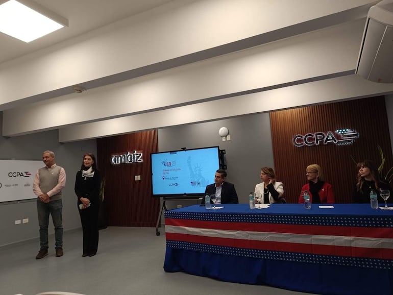 Carson Villalba y Graciela Meza en un evento formal, rodeados de público y una mesa con mujeres vestidas elegantemente, discutiendo sobre estilo de vida saludable.