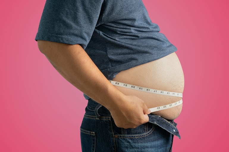 Hombre con obesidad se toma las medidas en la cintura.