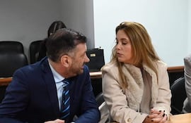 Edgardo Kueider en traje oscuro y corbata a rayas, junto a Iara Guinsel con abrigo claro, en conversación atenta en ambiente interior.