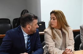 Edgardo Kueider en traje oscuro y corbata a rayas, junto a Iara Guinsel con abrigo claro, en conversación atenta en ambiente interior.