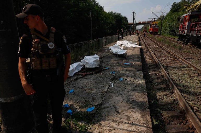 Un policía junto a los cuerpos de personas fallecidas en un bombardeo ruso en Kiev, el pasado miércoles.