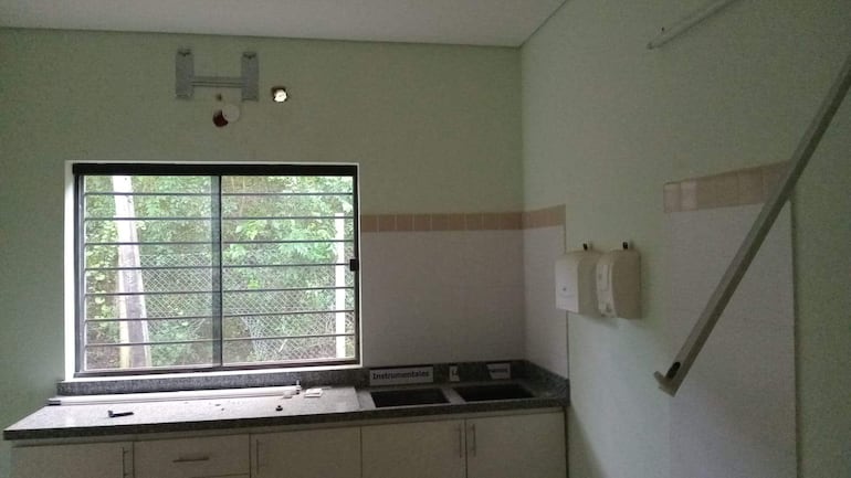 Cocina desordenada en la USF de La Victoria, con ventana hacia área verde, azulejos claros y letreros visibles.