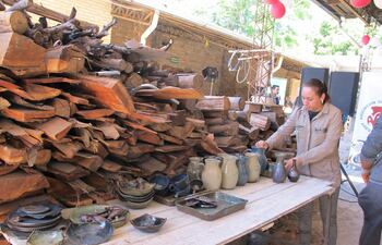 mujer colocando piezas de cerámica esmaltada, al costado leñas