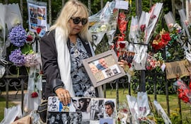 Isabelle, una fan de Alain Delon, posa con fotografías frente a la propiedad donde residía el actor en Douchy. La gente dejó flores y rindió homenaje a Delon fallecido ayer a los 88 años.