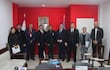 Grupo de ocho personas vestidas formalmente, en un ambiente interior, dialogando sobre integración fronteriza con rostros serios y atentos.