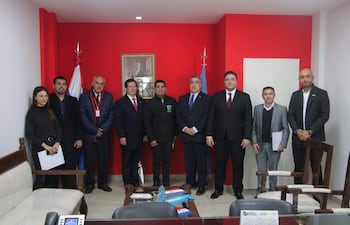 Grupo de ocho personas vestidas formalmente, en un ambiente interior, dialogando sobre integración fronteriza con rostros serios y atentos.