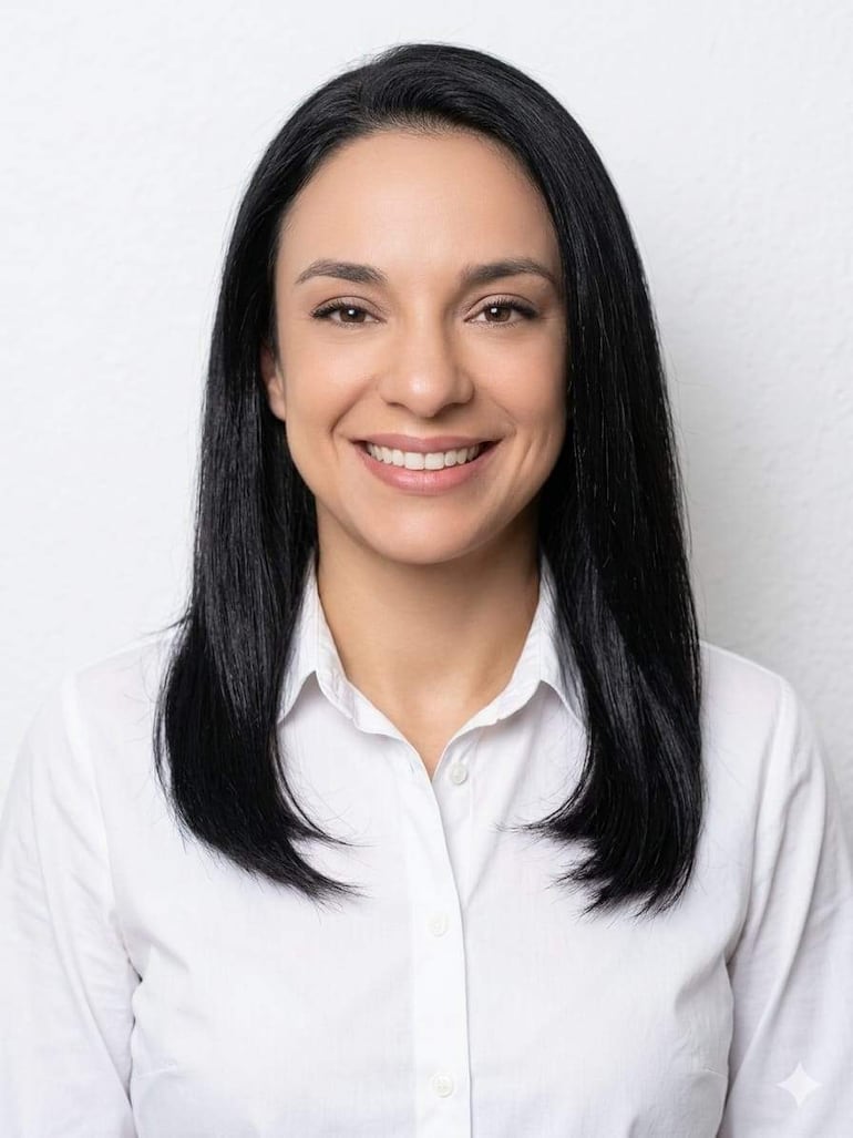 Hilda Gómez sonríe con cabello negro y camisa blanca, en un fondo claro, transmitiendo felicidad en un retrato oficial.