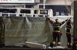 Los bomberos colocan lonas frente a las partes carbonizadas de un autobús postal tras incendiarse en Chiètres Suiza.