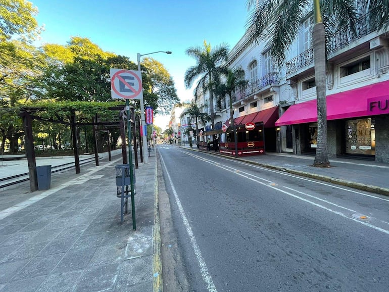 Calle vacía con tiendas de toldos coloridos y estructura de madera, sin personas ni vehículos visibles.