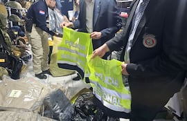 Agentes del Departamento Especializado contra la Violación de Derechos Intelectuales muestran los chalecos policiales que fueron incautados.